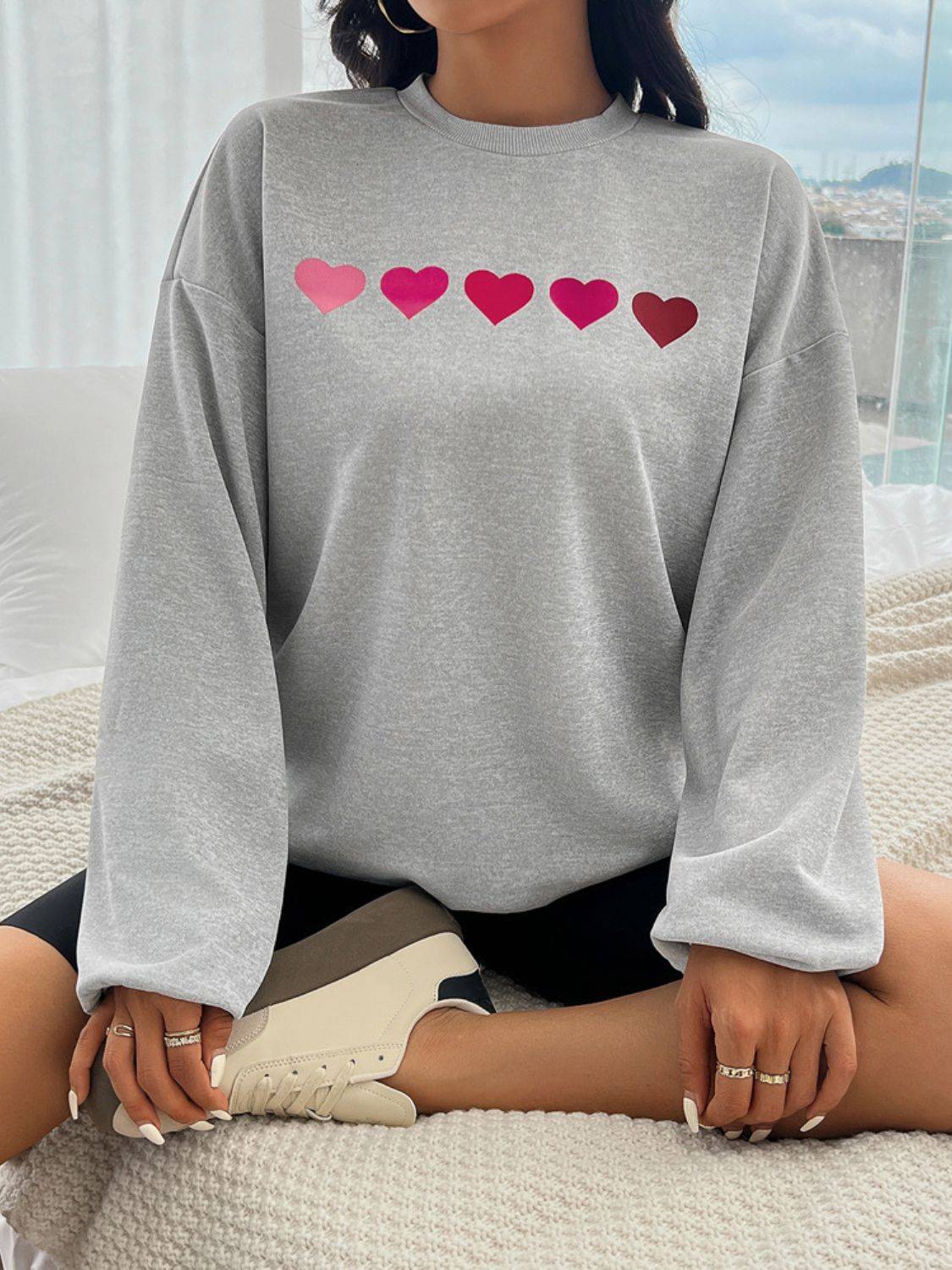 Gray sweatshirt with pink heart design on front.