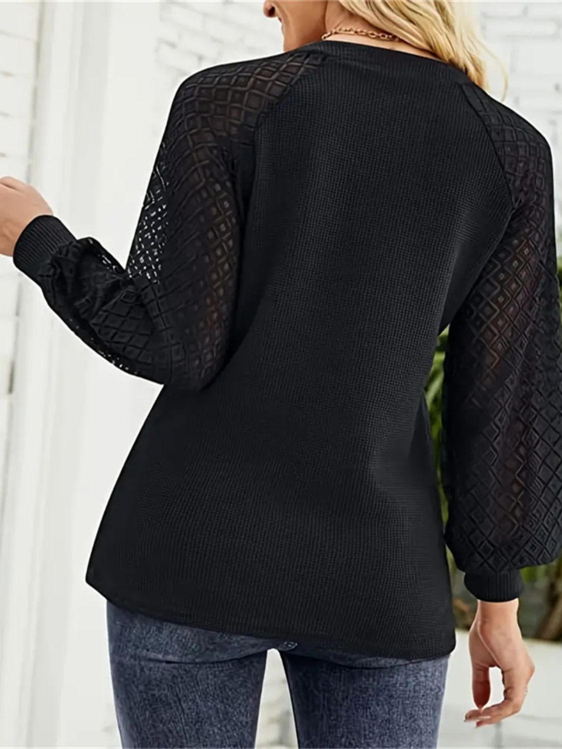 Back view of black V-neck t-shirt with lace sleeves.