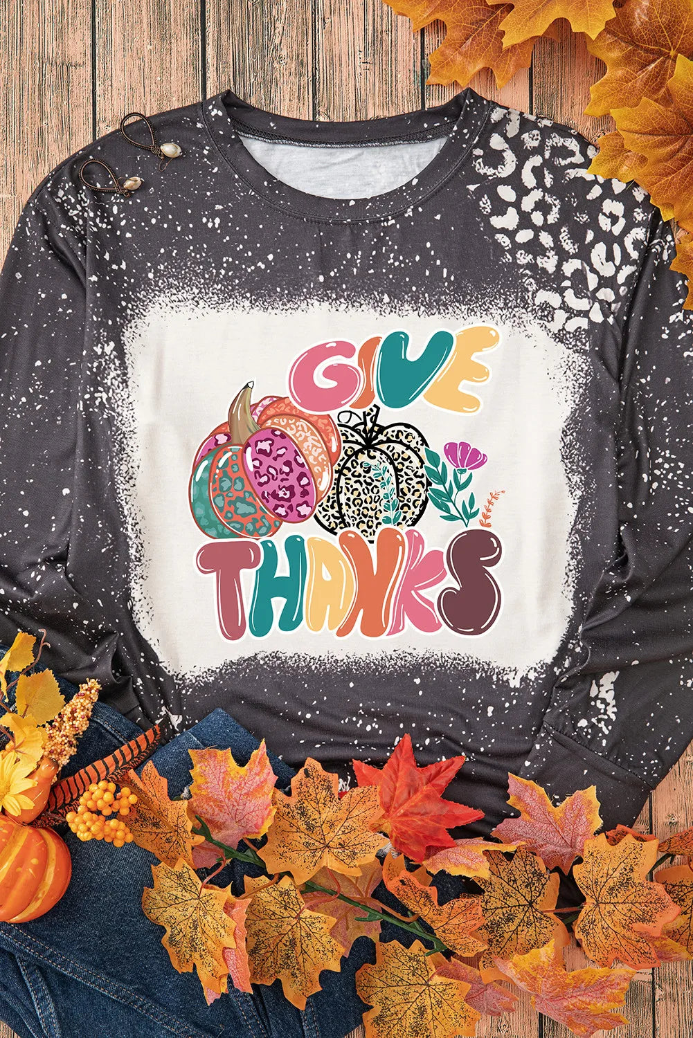 Flat lay of pumpkin graphic T-shirt with autumn leaves