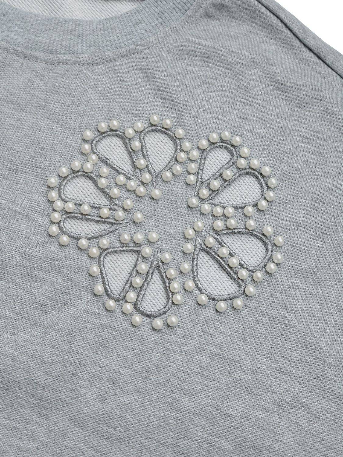 Close-up of pearl cutout design on gray sweatshirt