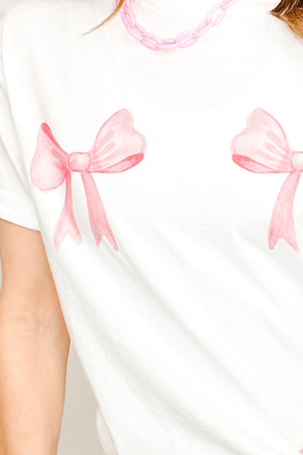 Close-up of pink bow graphic on white T-shirt