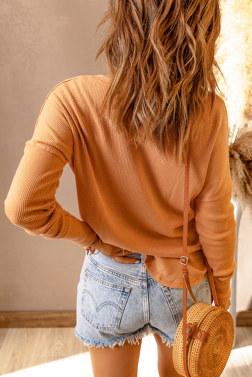 Back view of peach drop shoulder T-shirt and denim shorts.