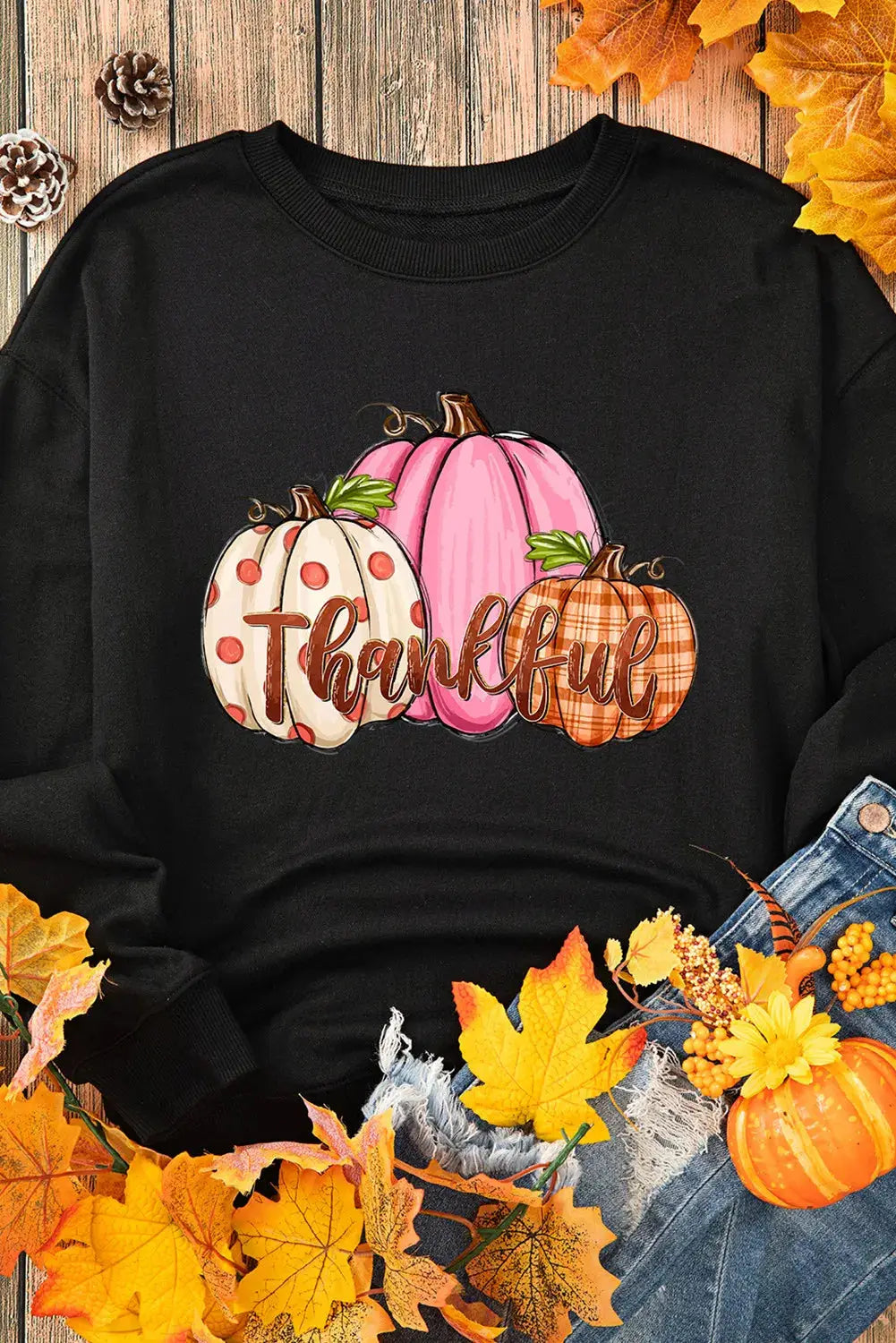 Flat lay of black sweatshirt with pumpkin graphic and fall decor