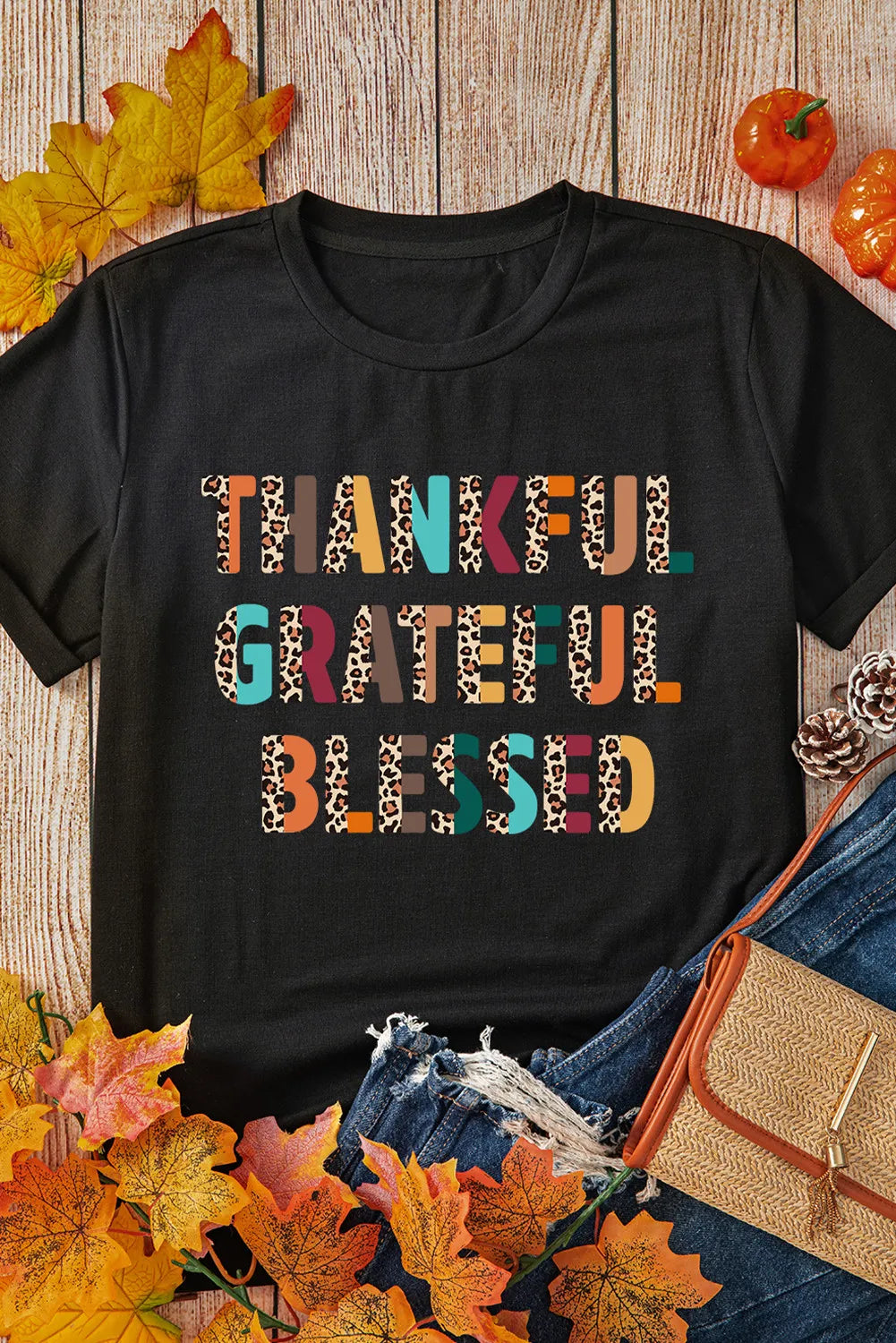 Flat lay of black T-shirt with autumn leaves