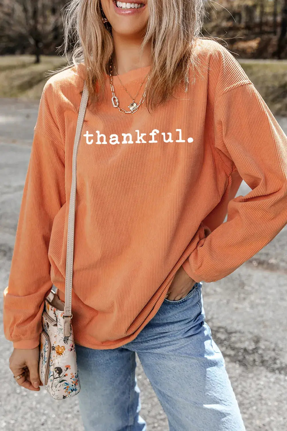 THANKFUL orange sweatshirt styled with jeans, front view