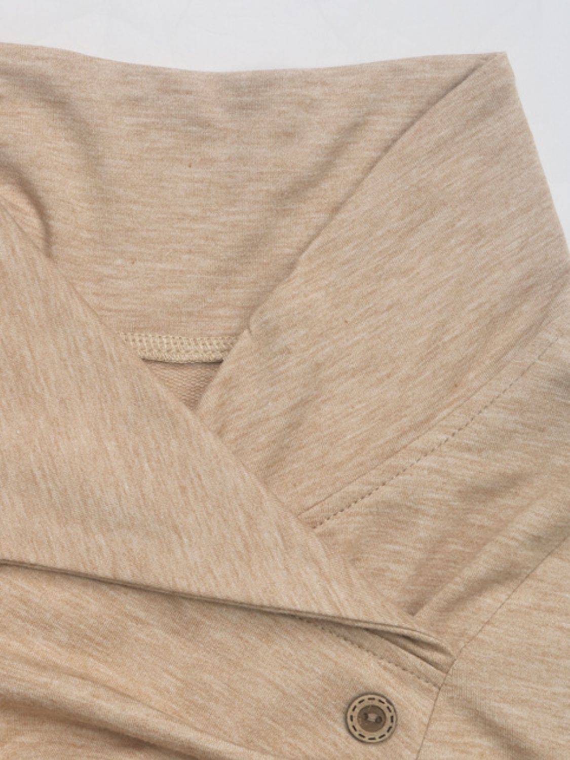 Close-up of beige mock neck sweatshirt fabric and buttons.