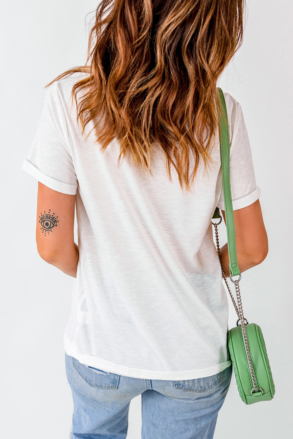 Back view of white T-shirt, paired with green bag.
