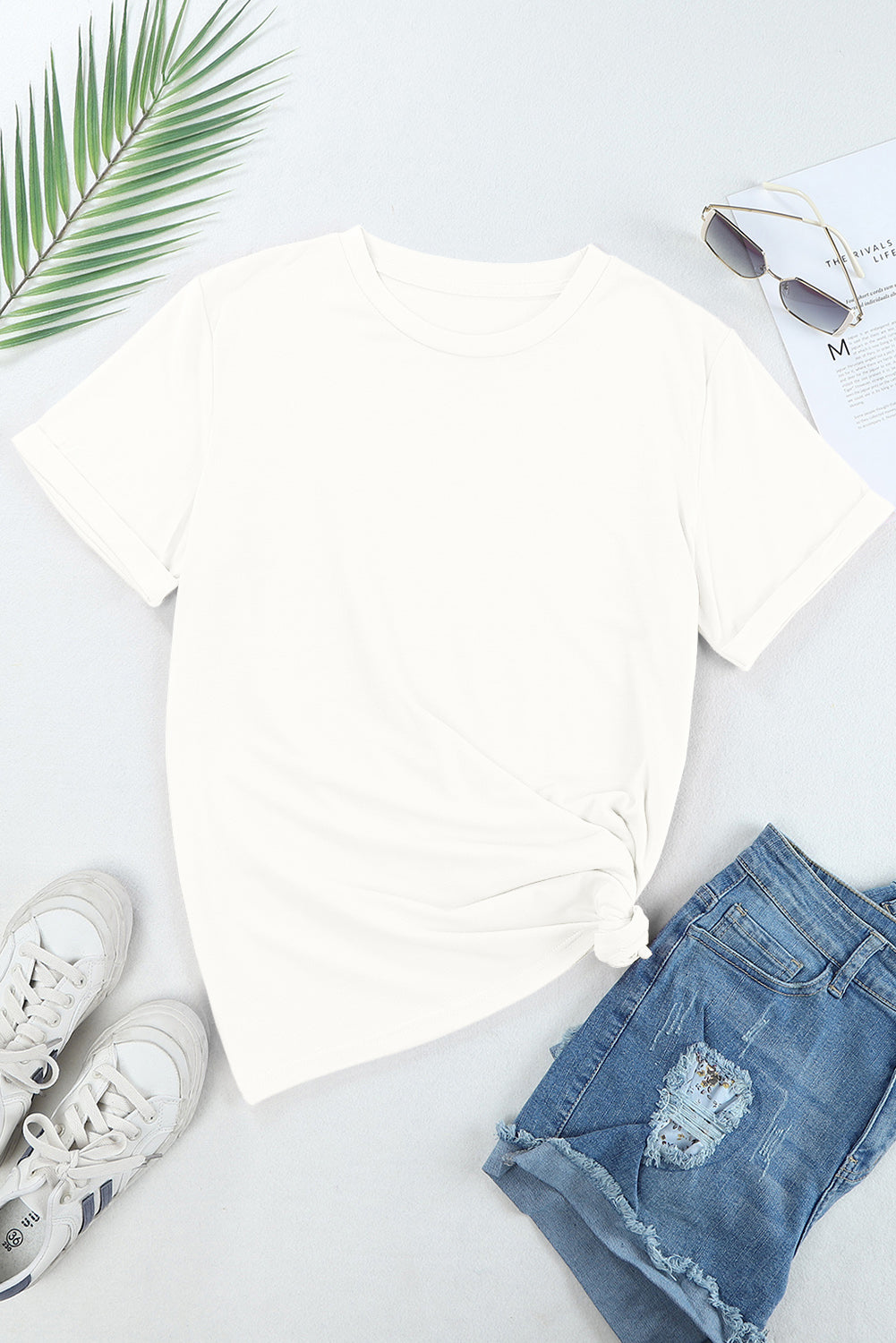 Plain white T-shirt styled with denim shorts and sneakers.