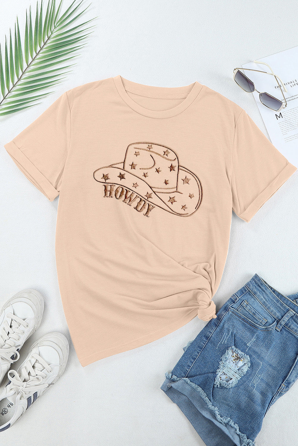 Flat lay of beige t-shirt with hat graphic, paired with jeans.