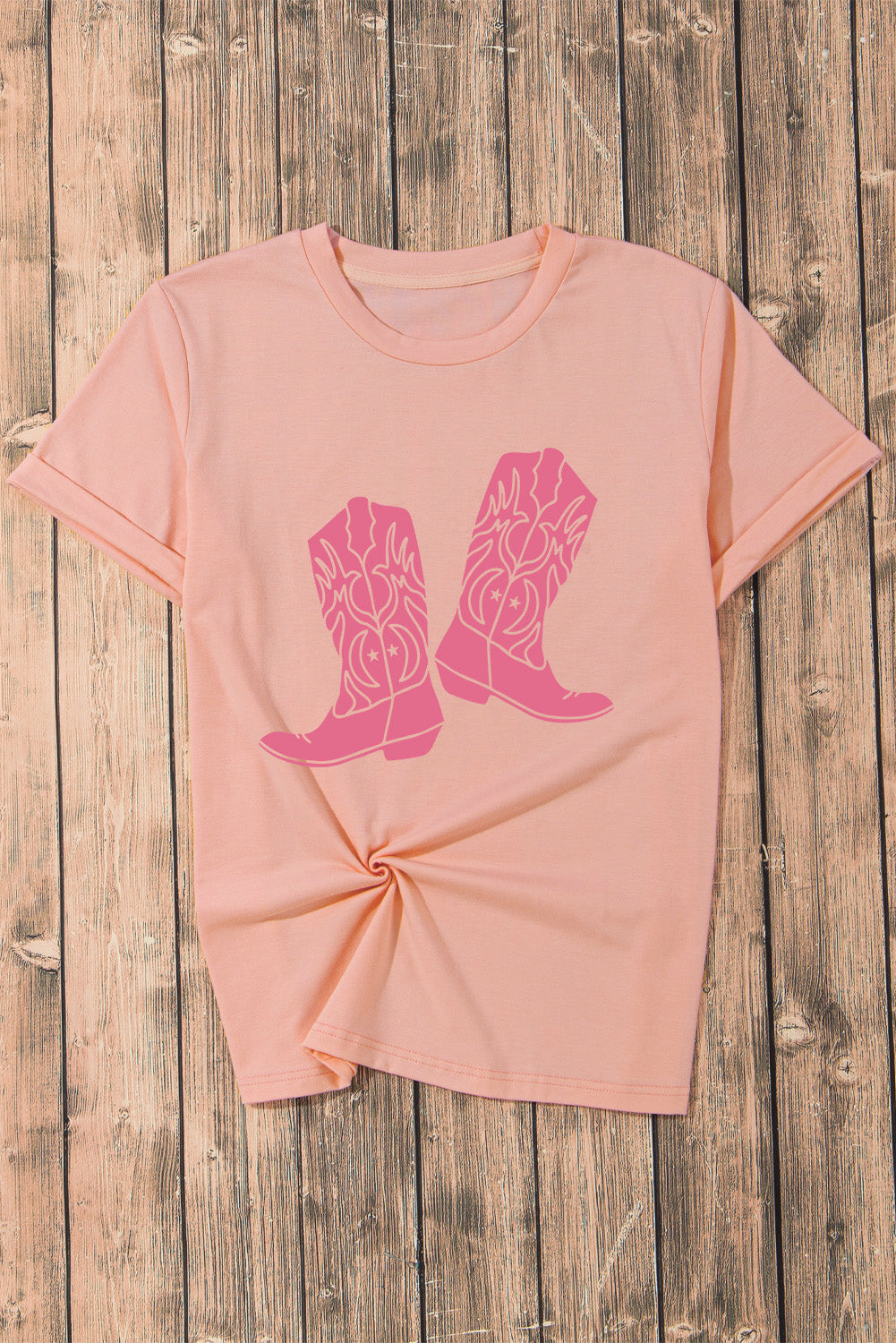 Flat lay of pink T-shirt with boots graphic, round neck