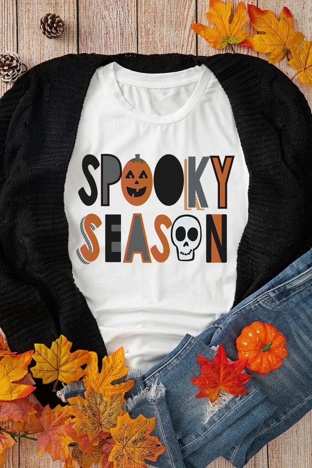Flat lay of Spooky Season T-shirt with autumn leaves.