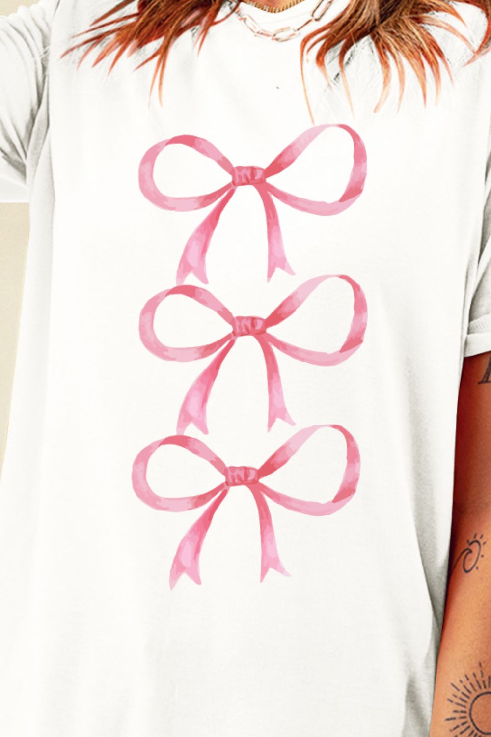 Close-up of pink bow graphic on white T-shirt.