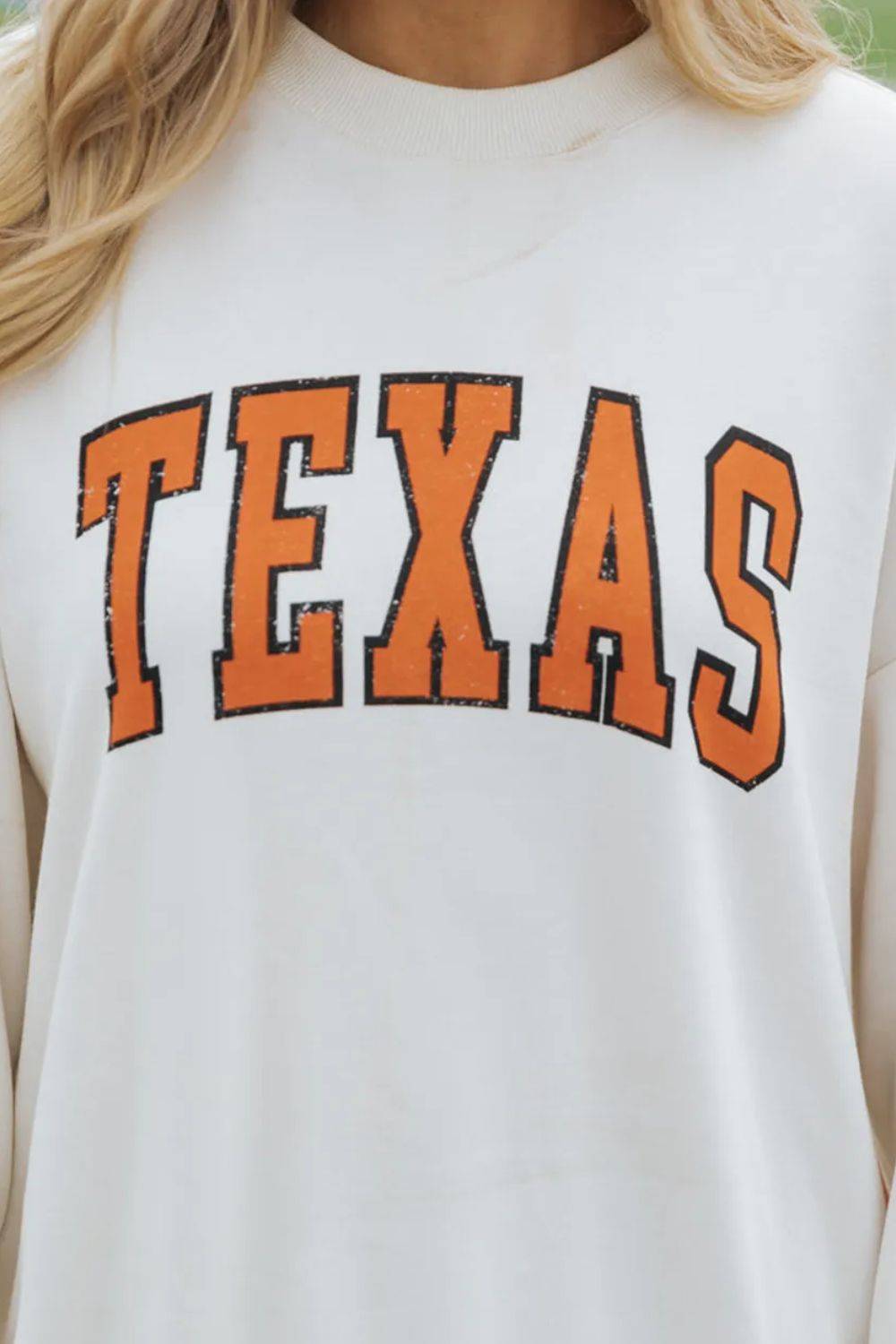 Close-up of TEXAS lettering on white sweatshirt.