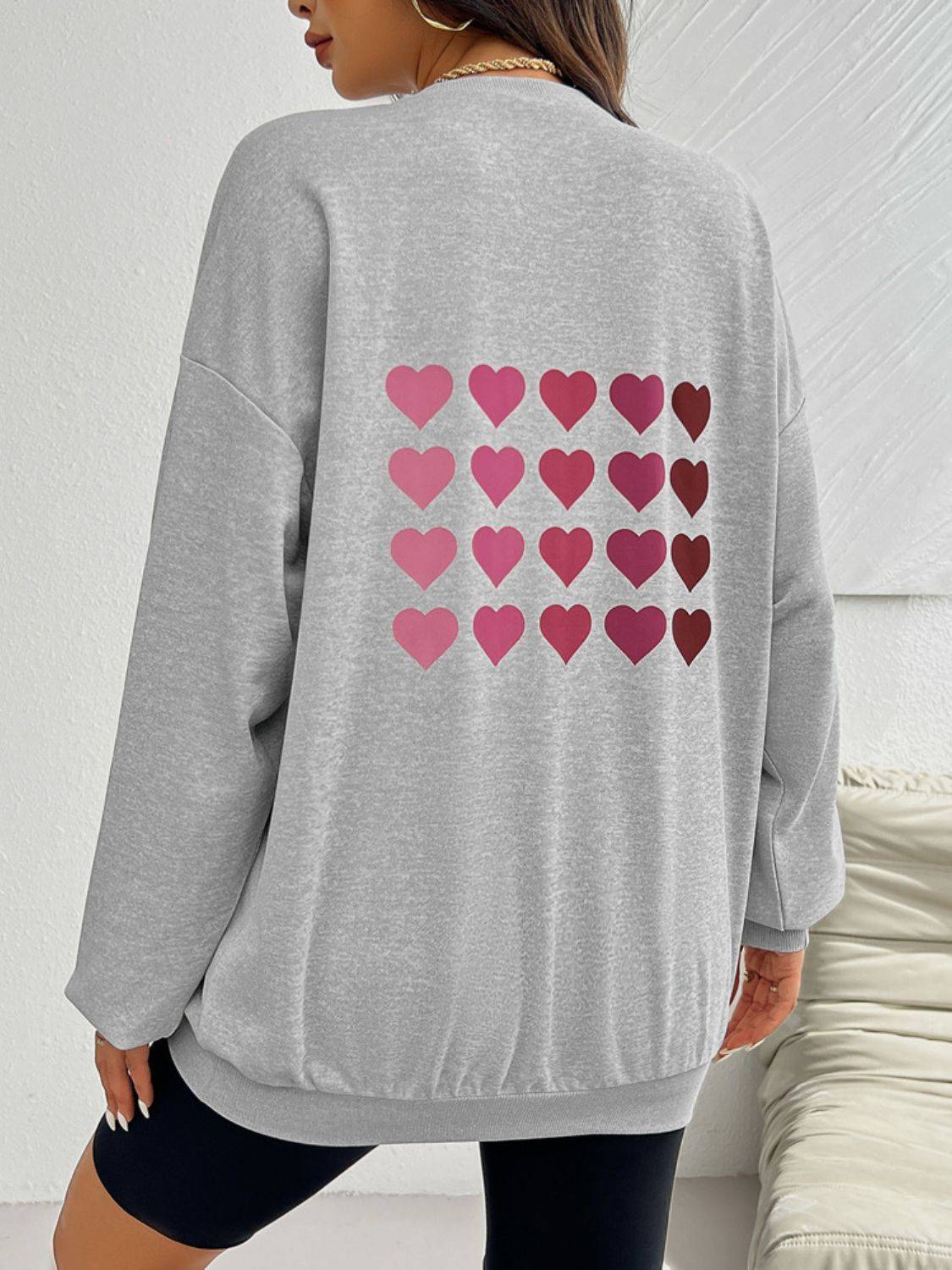 Back view of gray sweatshirt with multiple pink hearts.