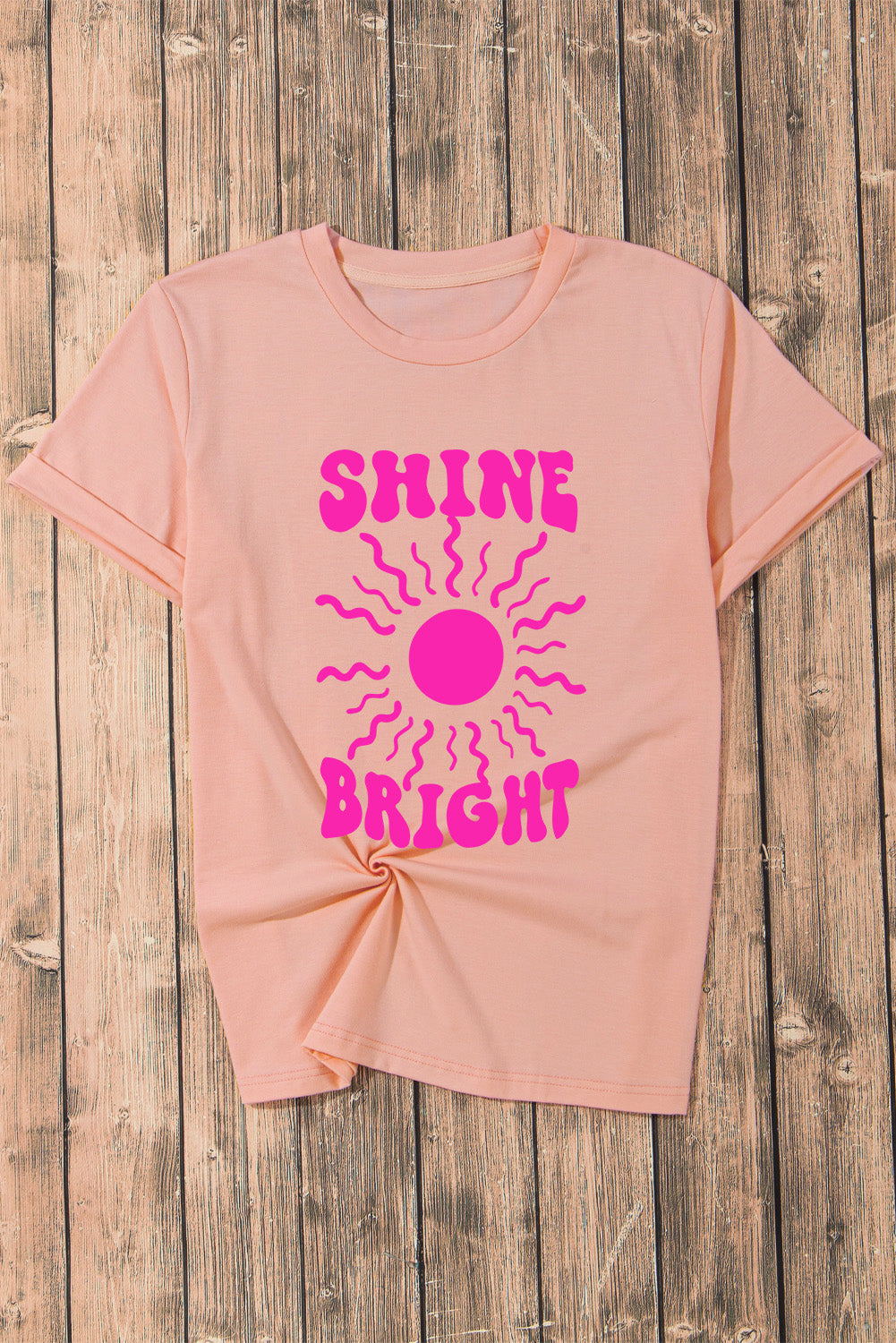 Flat lay of SHINE BRIGHT T-shirt on wooden surface
