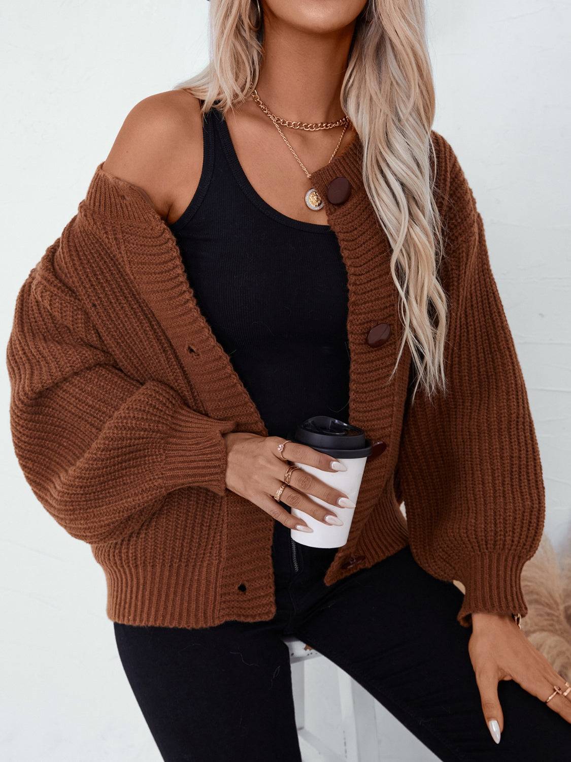 Brown cardigan with black top holding a cup