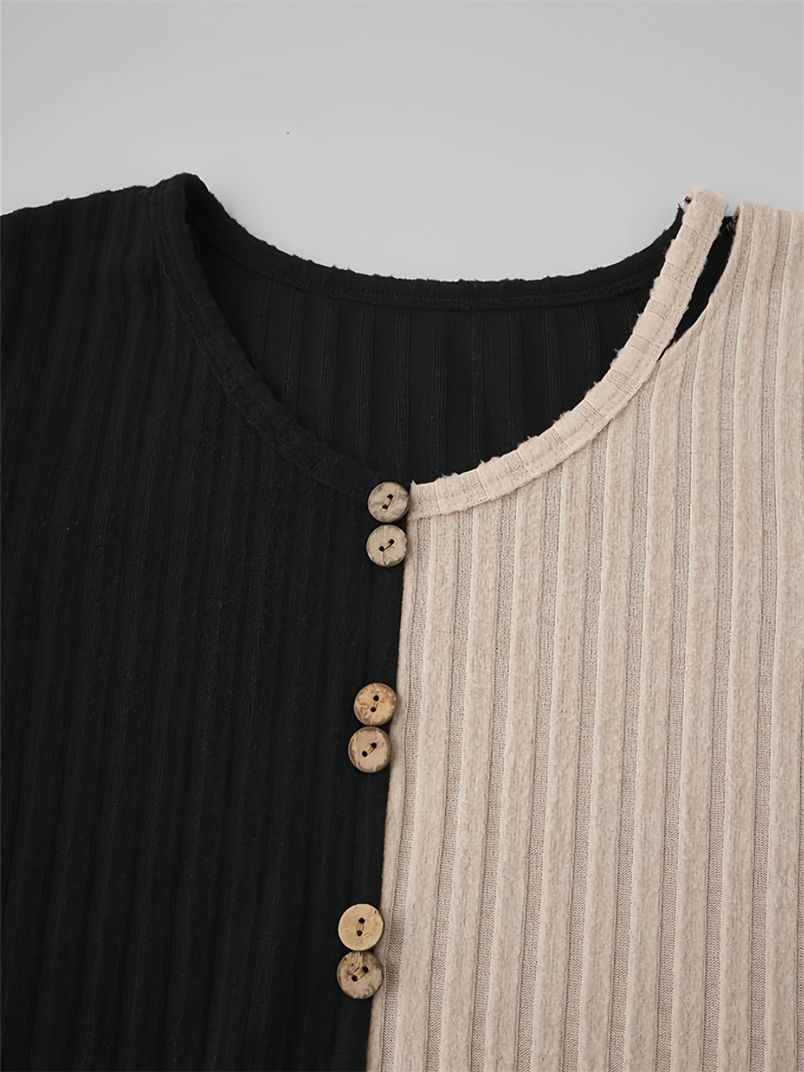 Close-up of round neck and buttons on two-tone T-shirt.