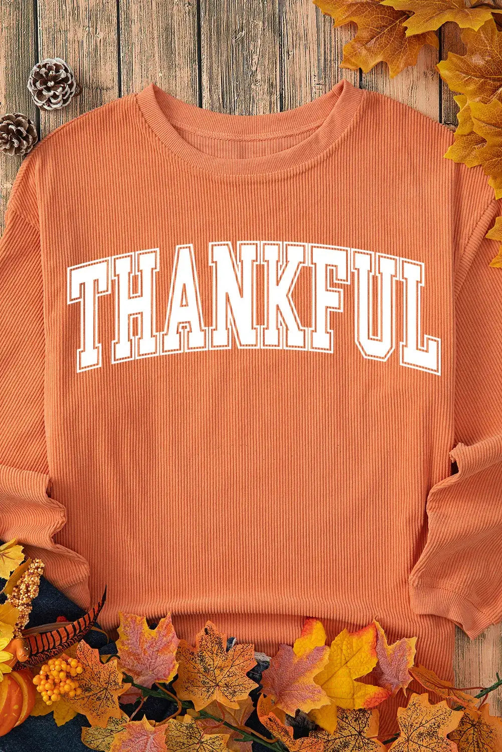 THANKFUL orange sweatshirt displayed with autumn leaves