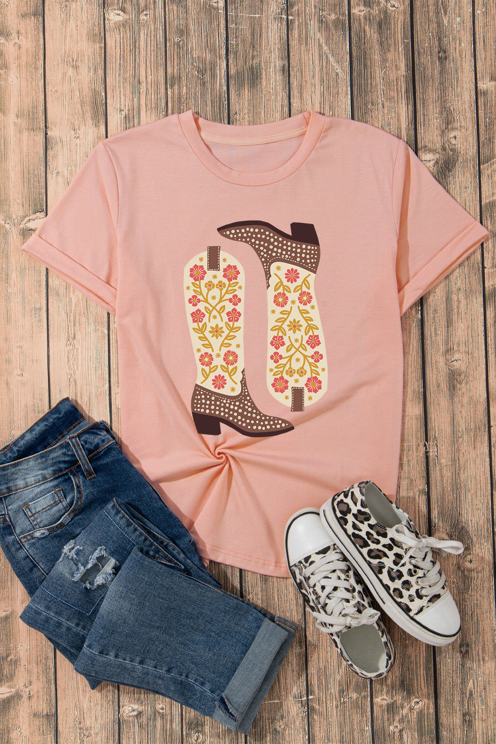 Flat lay of pink T-shirt with boot graphic, jeans, sneakers