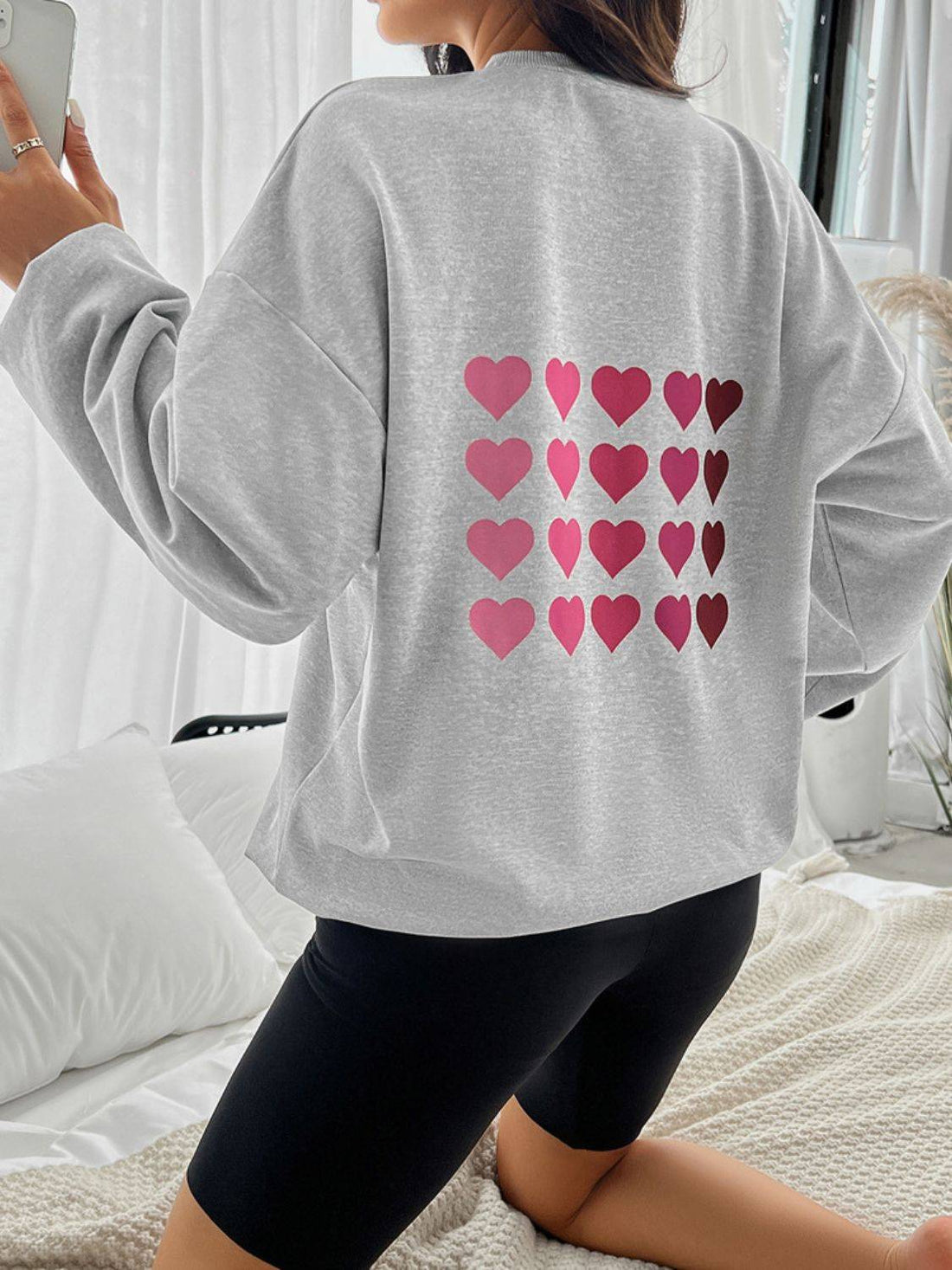 Back view of gray sweatshirt with multiple pink hearts.