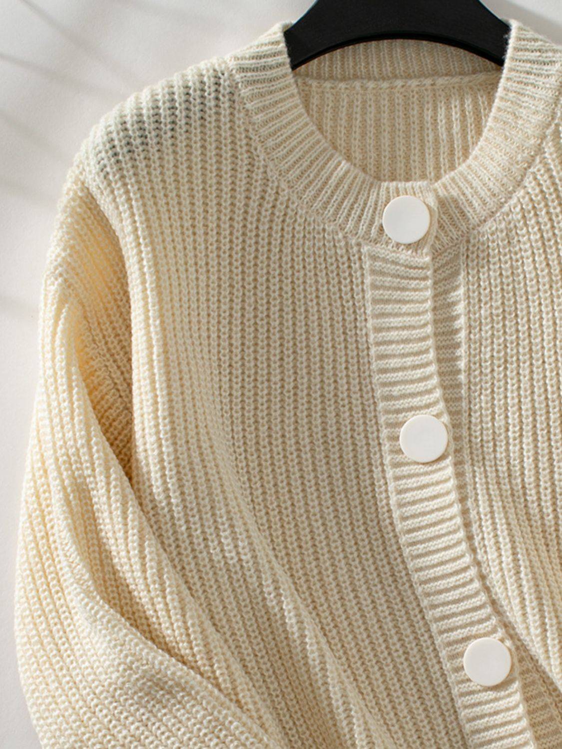 Close-up of cream button down cardigan on hanger