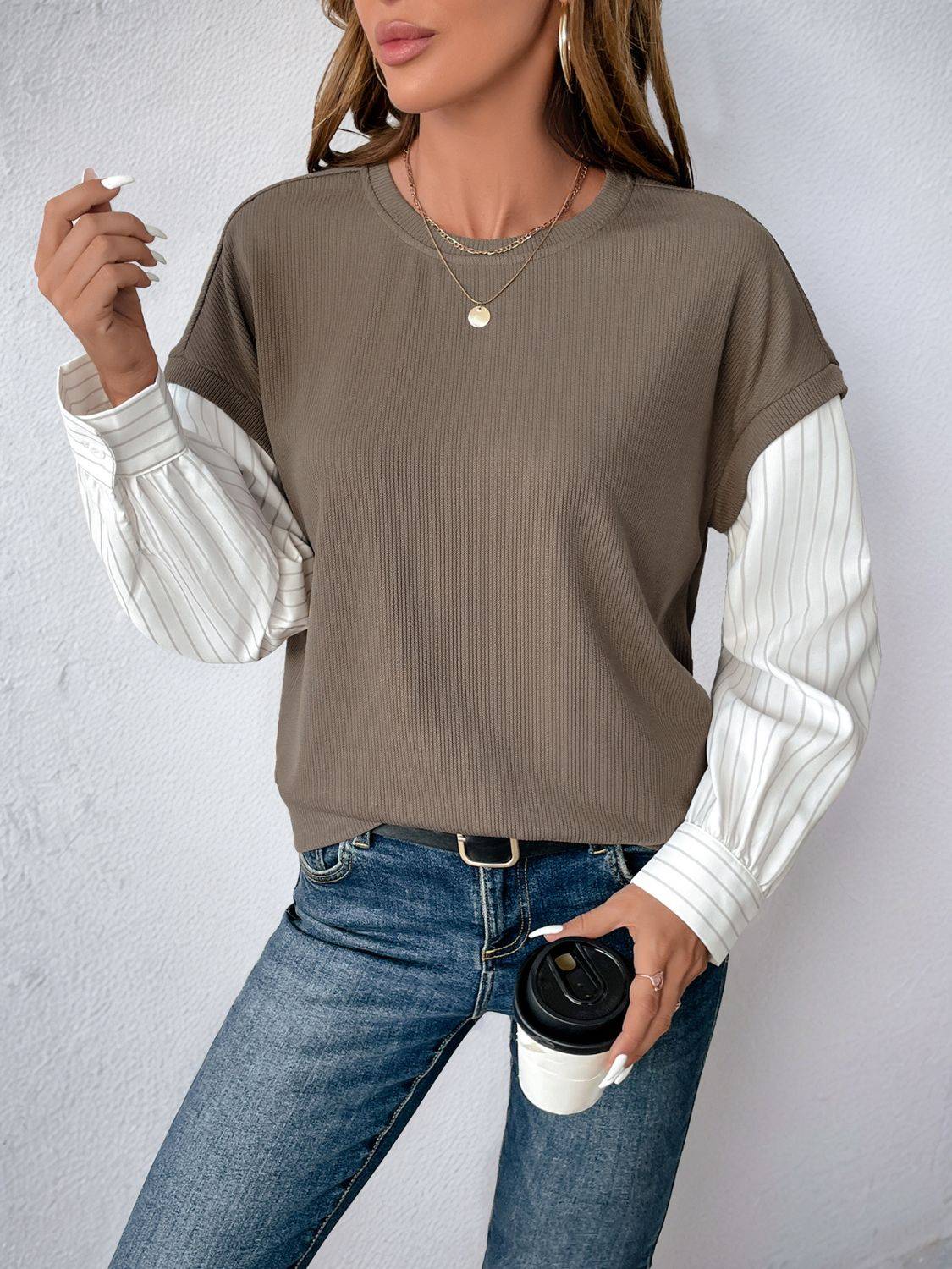 Perfee sweatshirt with striped sleeves, holding coffee