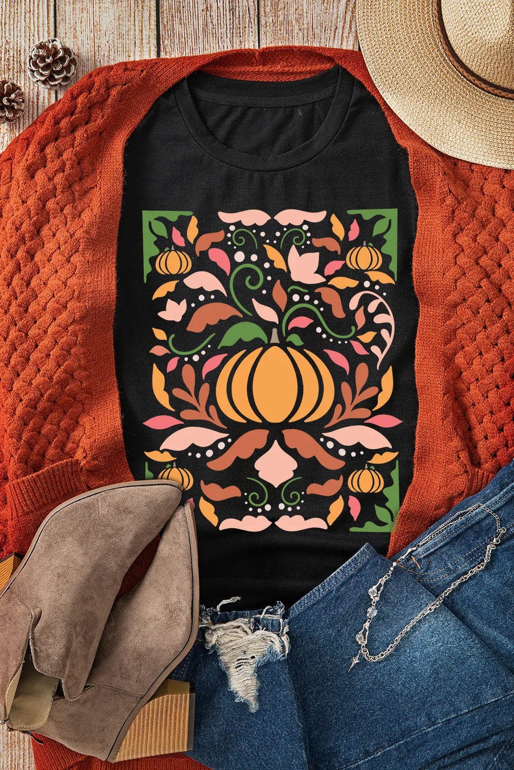 Flat lay of black graphic t-shirt with pumpkin design and accessories