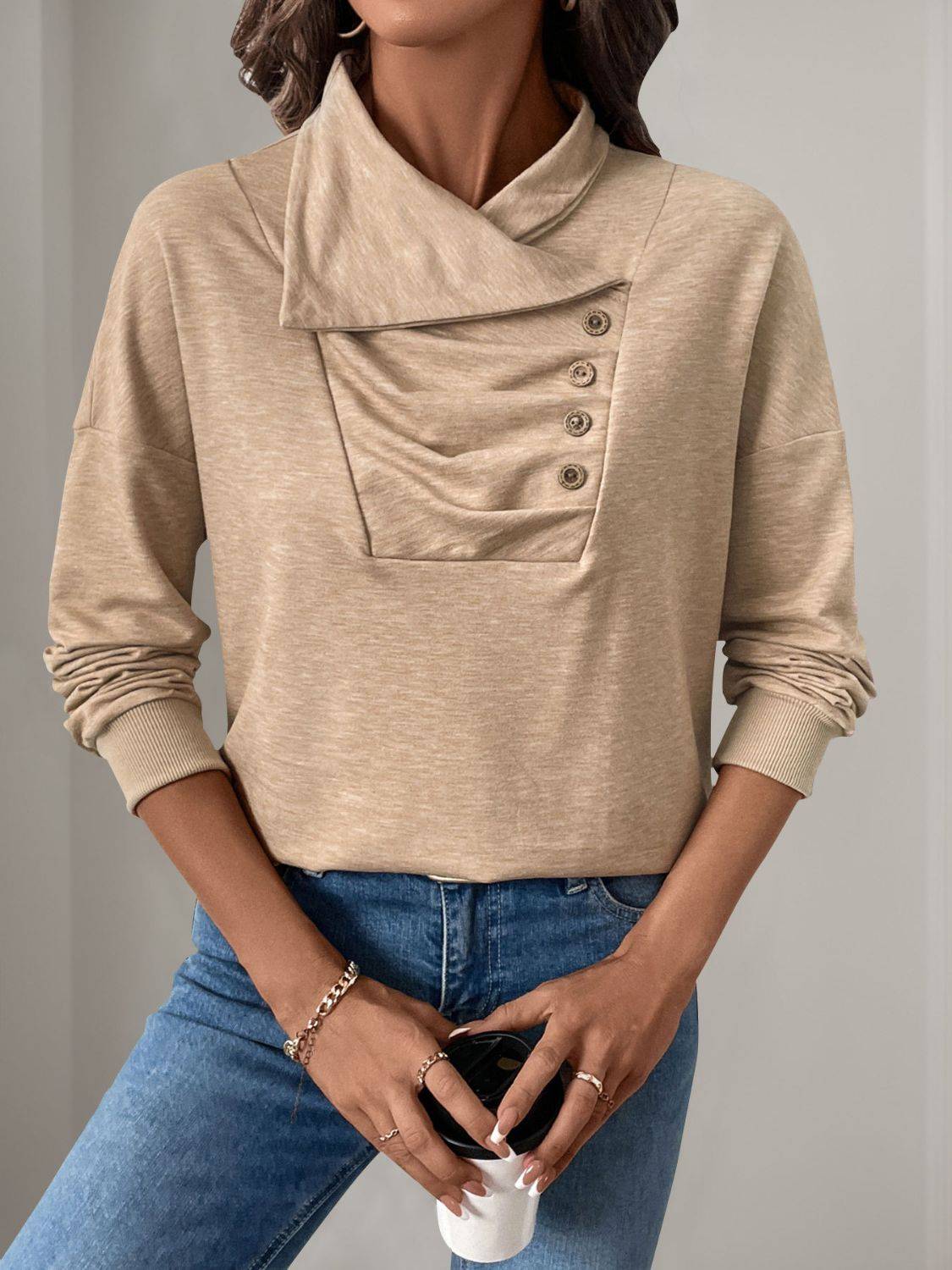 Beige asymmetric mock neck sweatshirt with button detail.