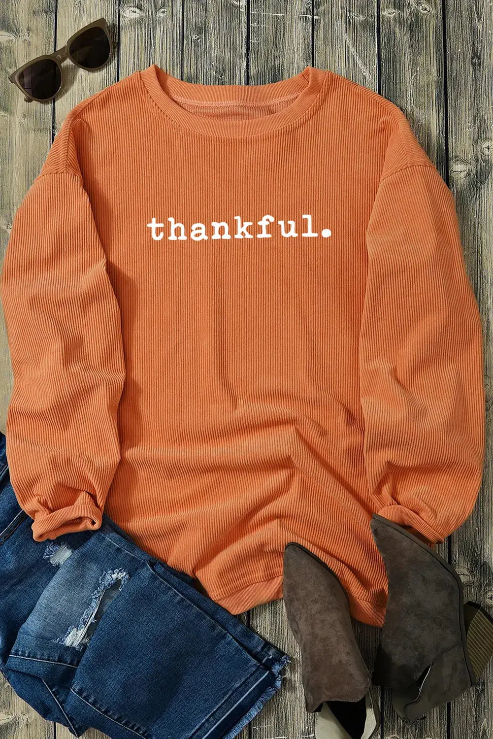 THANKFUL orange sweatshirt laid flat with jeans and boots