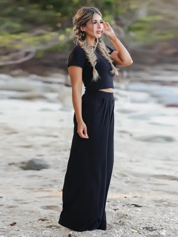 Model in black two-piece set on beach, side view
