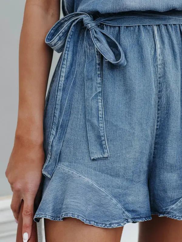 Detail of denim jumpsuit with bow tie waist