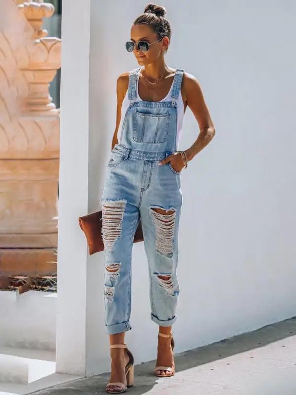 Woman wearing washed ripped blue overalls jeans, sunglasses