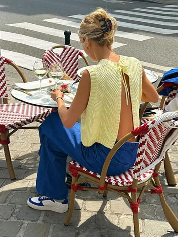 Woman wearing yellow knitted backless vest top at outdoor cafe