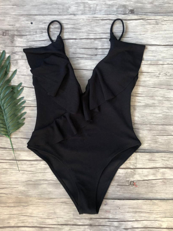 Black ruffled one-piece swimsuit on wooden background
