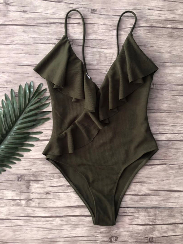 Green ruffled one-piece swimsuit on wooden background
