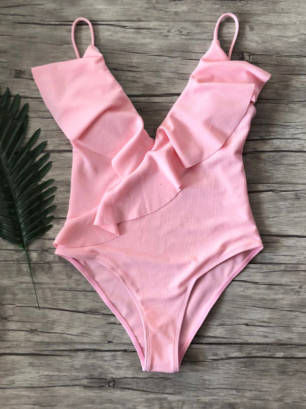 Pink ruffled one-piece swimsuit on wooden background