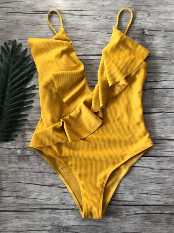 Yellow ruffled one-piece swimsuit on wooden background