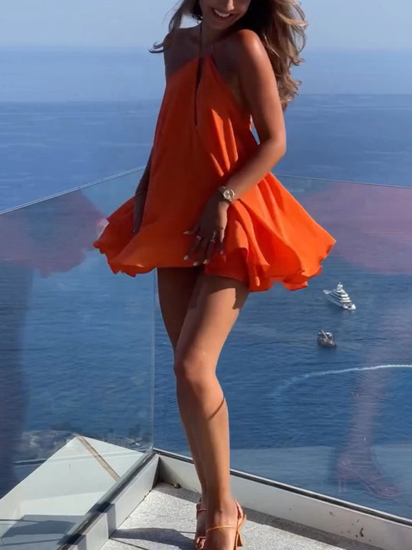 Woman in orange A-line dress by ocean view