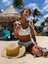 Woman in white bikini on beach with straw hat