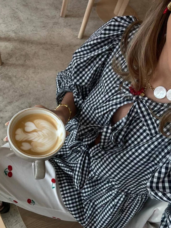 Close-up of checkered blouse and latte art