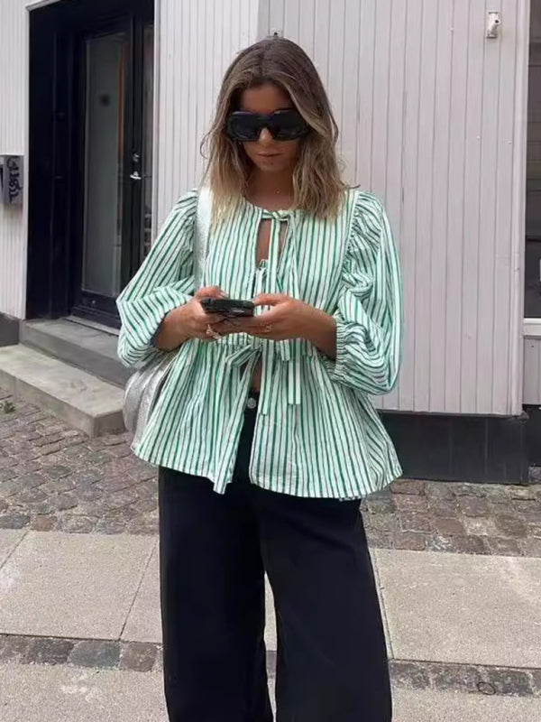 Woman in striped blouse using phone on street