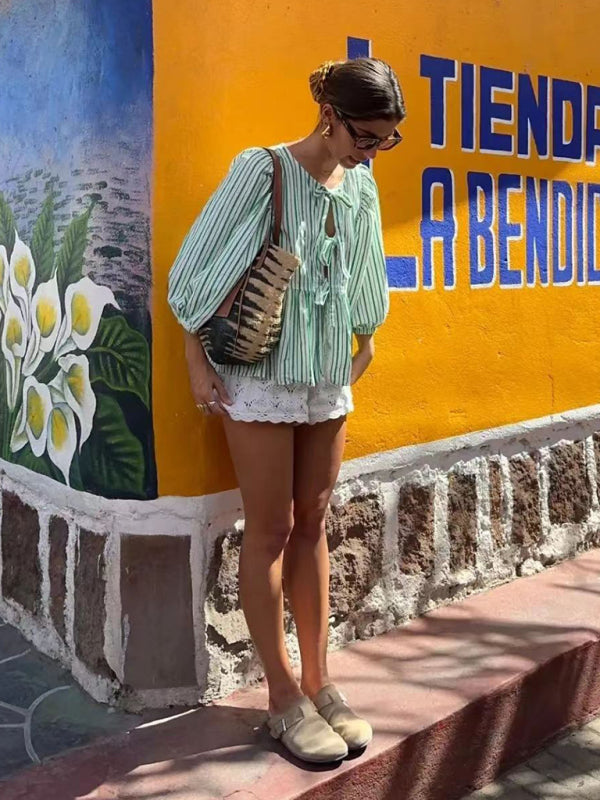 Woman in striped blouse and shorts by mural