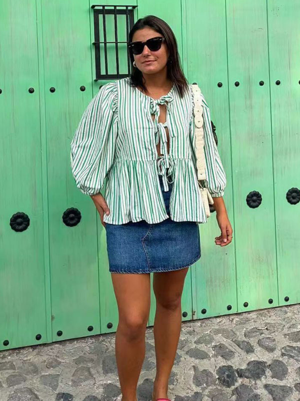 Woman in striped blouse and denim skirt by green door