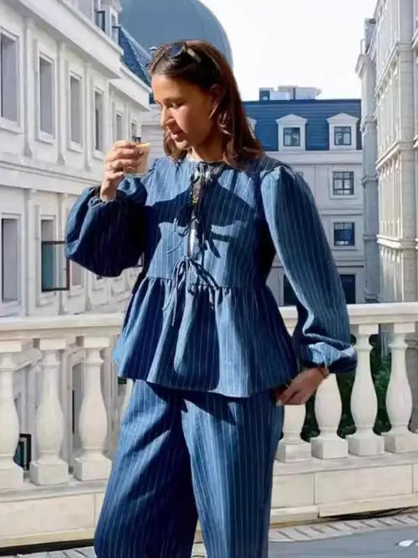 Woman drinking coffee in a blue striped lace-up top on a balcony