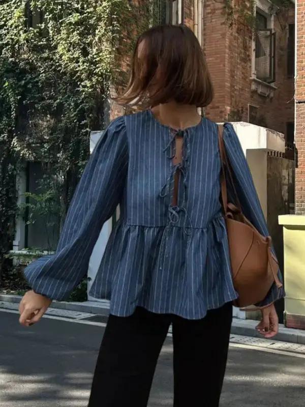 Woman in a blue striped lace-up top walking on a street