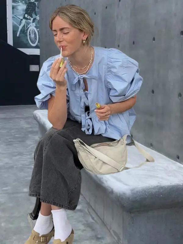 Light blue puff sleeve shirt with black pants sitting on bench