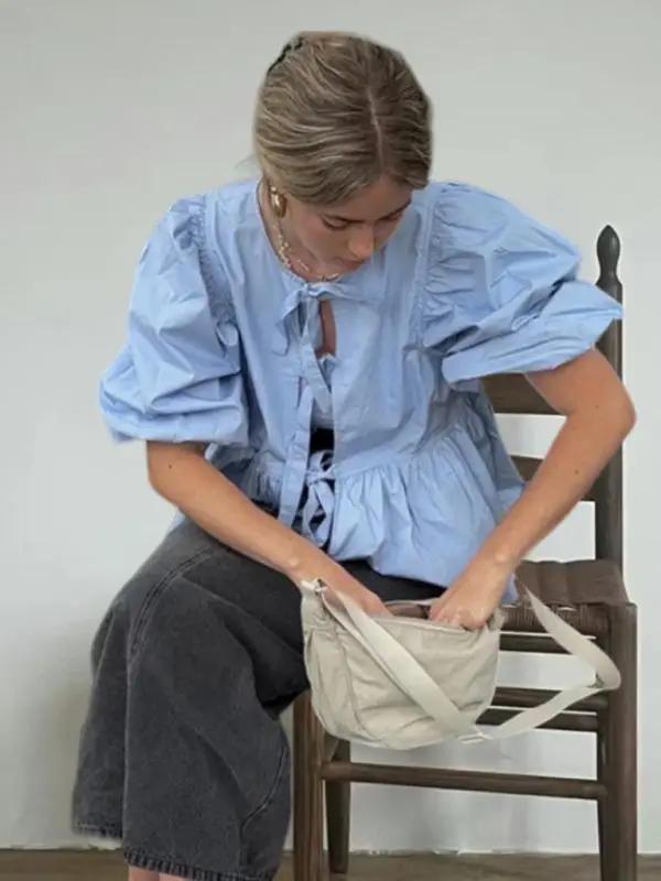 Light blue puff sleeve shirt with black pants sitting on chair