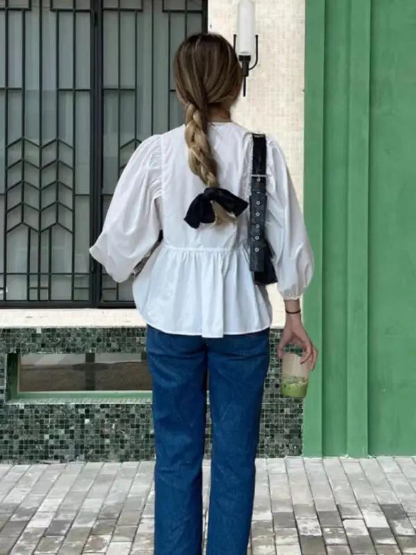 Back view of white puff sleeve shirt with black bow and jeans