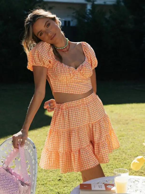 Smiling woman in orange plaid backless tie top and skirt