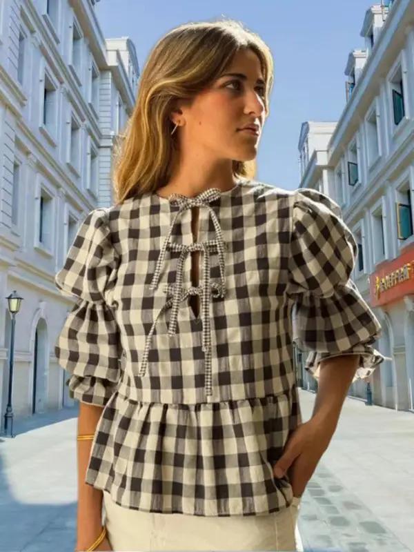 Woman wearing checkered puff sleeve blouse with tie detail